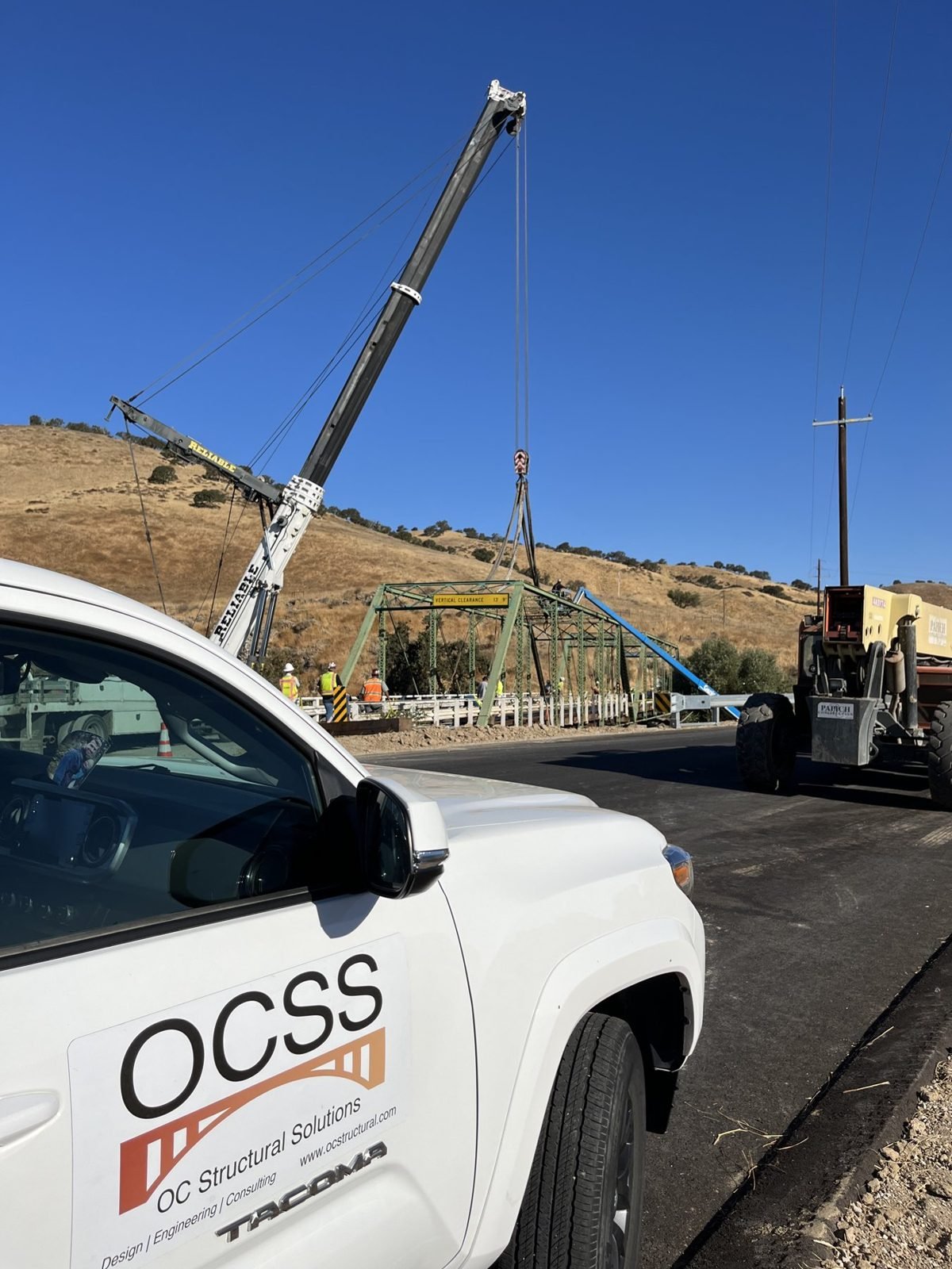 OCSS truck on site as a crane lifts a 1921 steel truss span